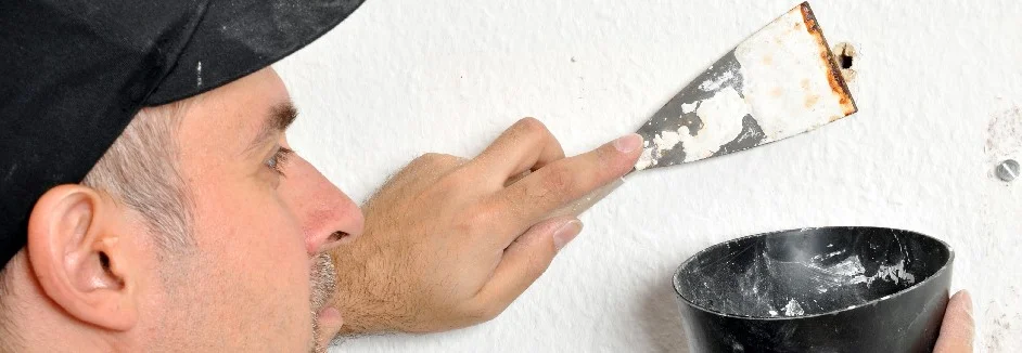 Person verspachtelt Loch in Wand